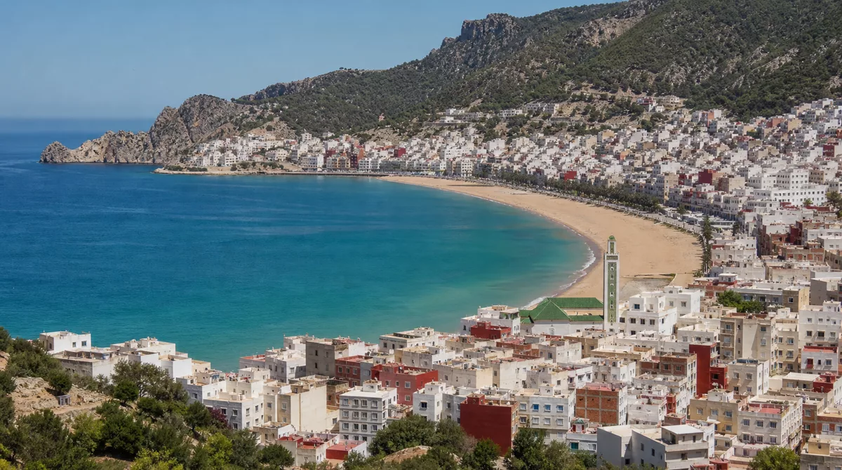 Turquoise Mediterranean bay at Al Hoceima with dramatic cliffs, a small sandy beach and the Rif mountains in the background
