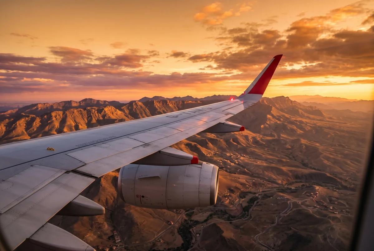 Airplane wing at sunset over Morocco with fuel gauge warning indicator overlay