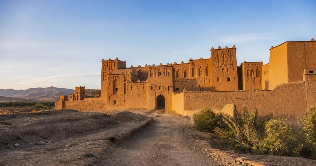 Kasbah de Taourirt à Ouarzazate au coucher du soleil, avec les montagnes de l’Atlas en arrière-plan