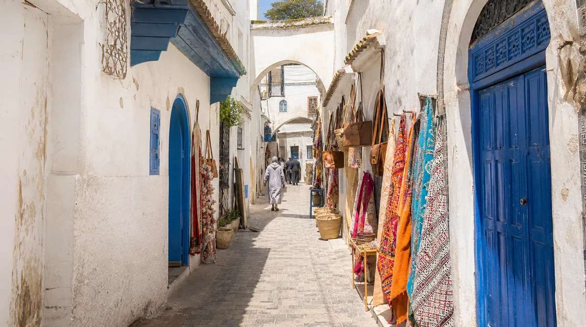 Narrow whitewashed alley in the Tétouan medina with blue doors and artisan workshops in soft morning light